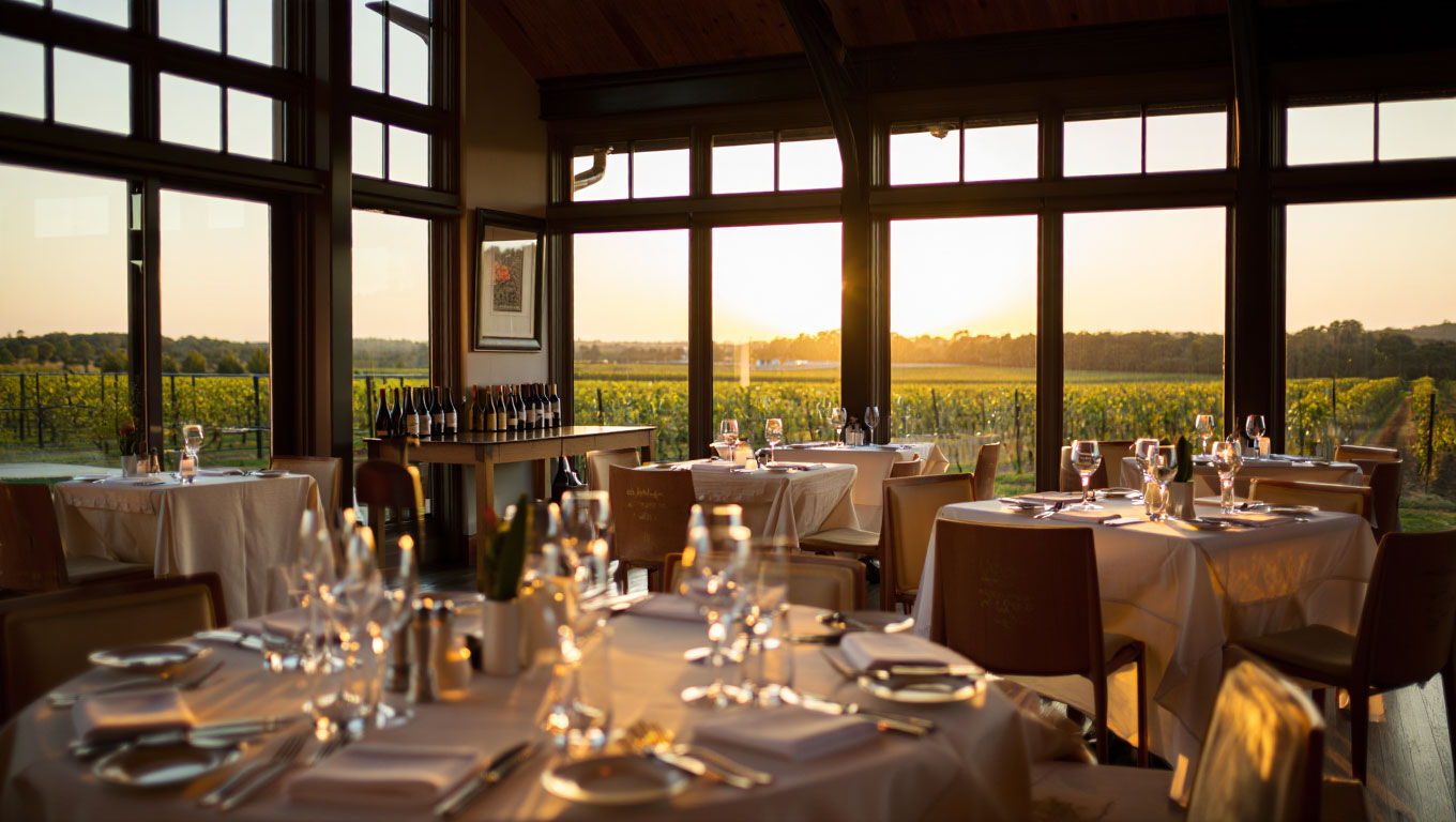 Quiet Michelin restaurant dining room in Napa Valley just before dinner service, showing linen tables, polished glassware, and a calm, refined atmosphere.