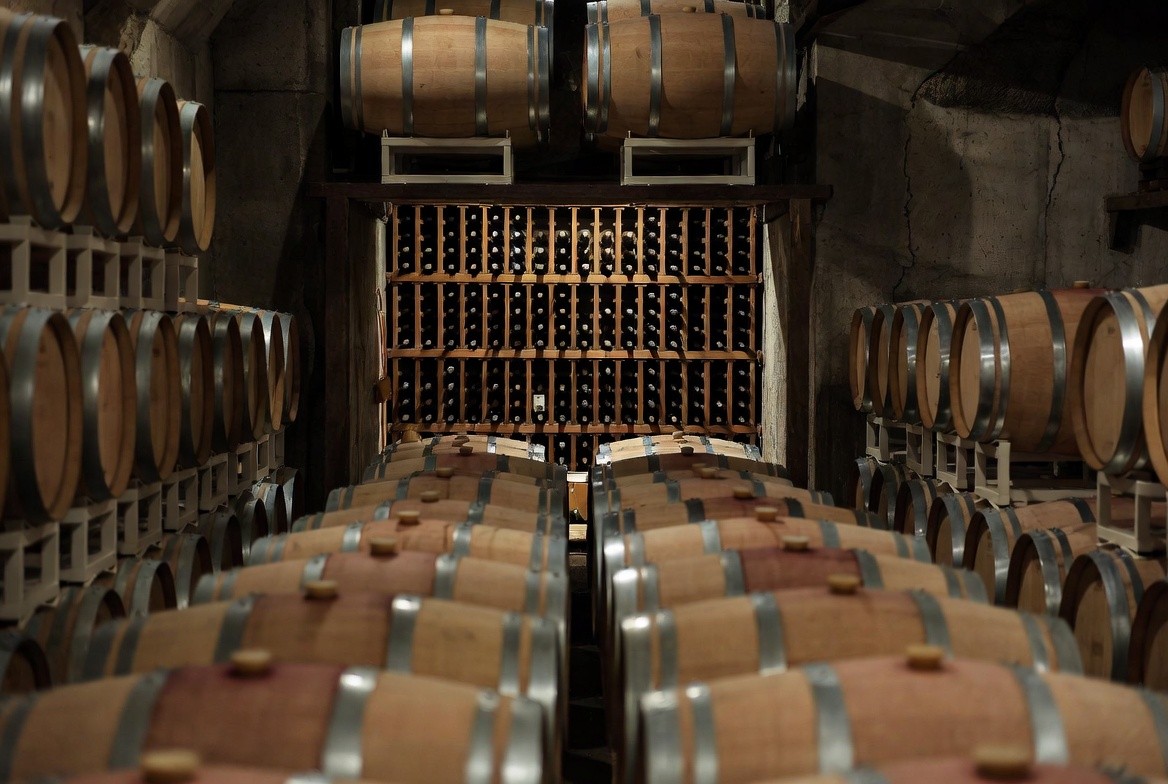 Winery cellar in Napa Valley with aging barrels and low lighting, illustrating wine maturation, patience, and long-term cellaring.